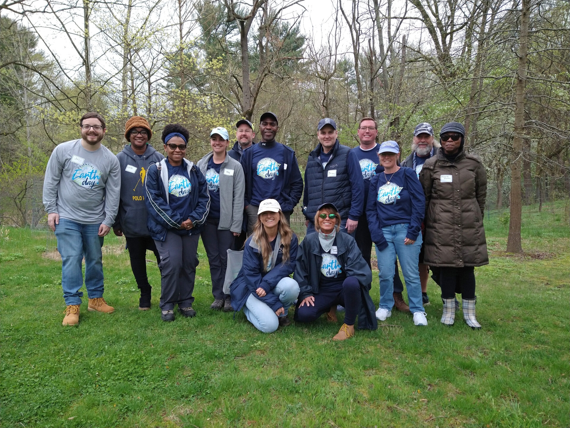 a group of smiling people with t-shirts that say "Earth Day" looking at the camera